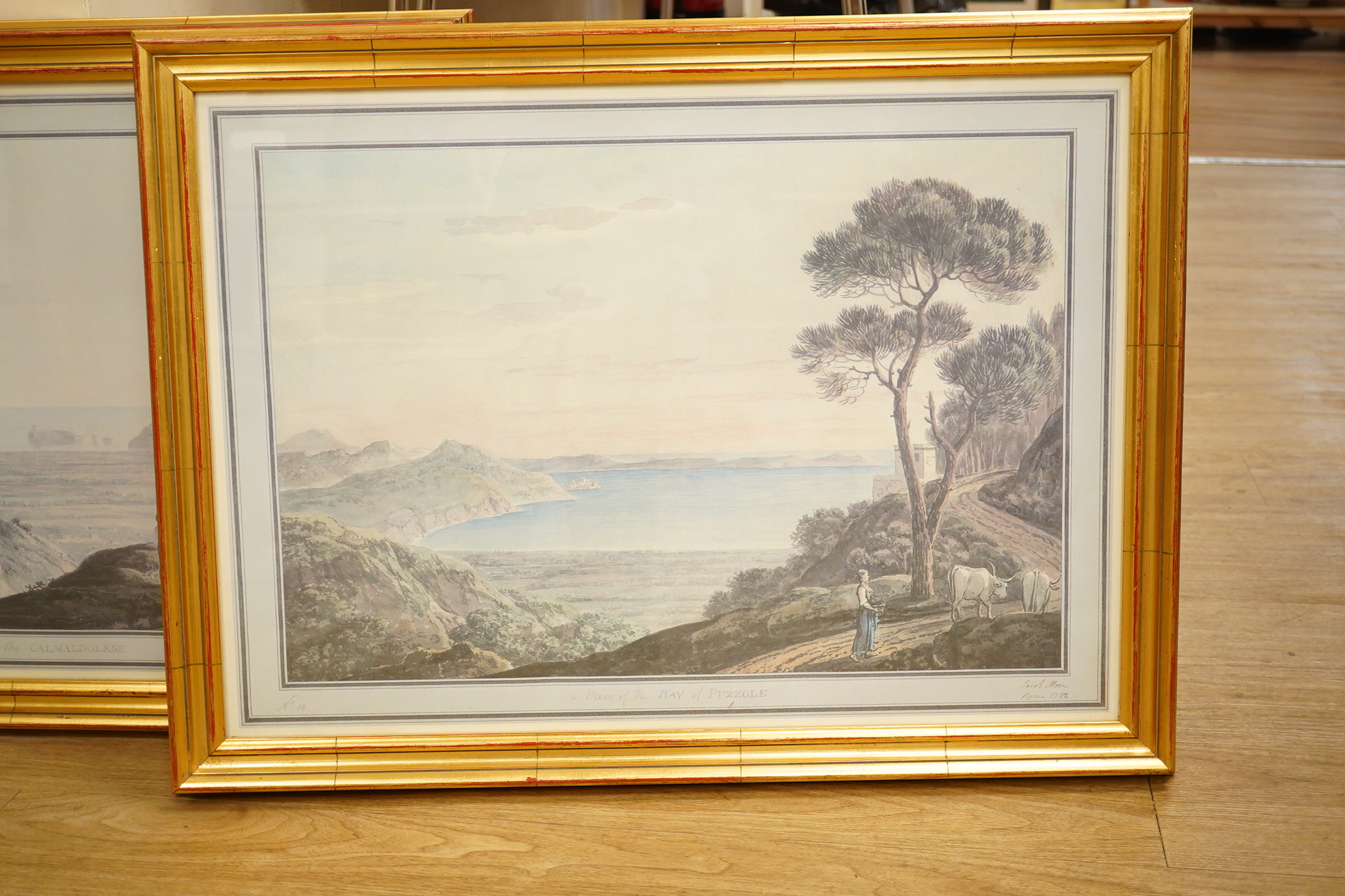 A pair of decorative prints comprising a ‘View of the Bay of Puzzole’ and ‘View near the Calmaldolese’, 48 x 68cm, gilt framed. Condition - good